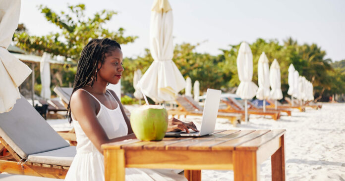 Woman working on laptop on beach